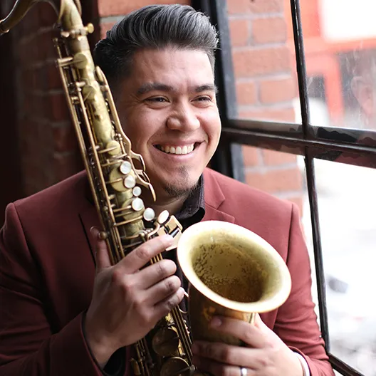 A man holding a saxophone and smiling