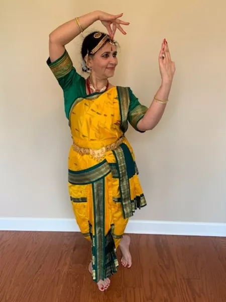 Bhavani Murthy doing a pose where she is holding a mirror and putting on jewelry and the Bindi (the red mark on the forehead).