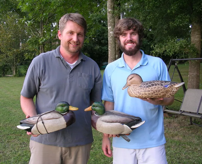 Men holding decoy ducks